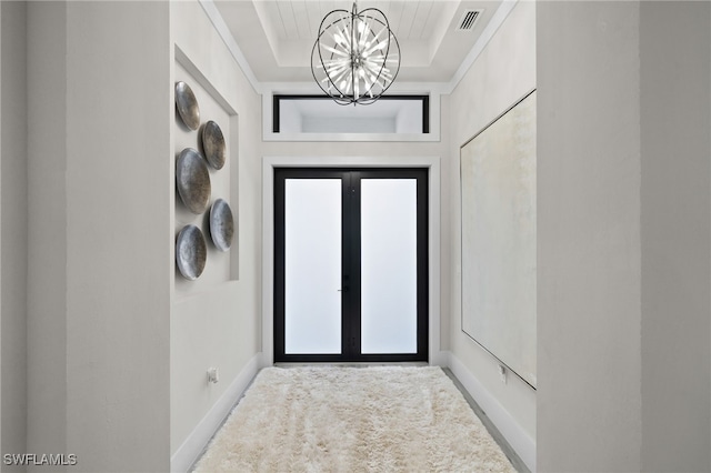 doorway with a notable chandelier and a raised ceiling