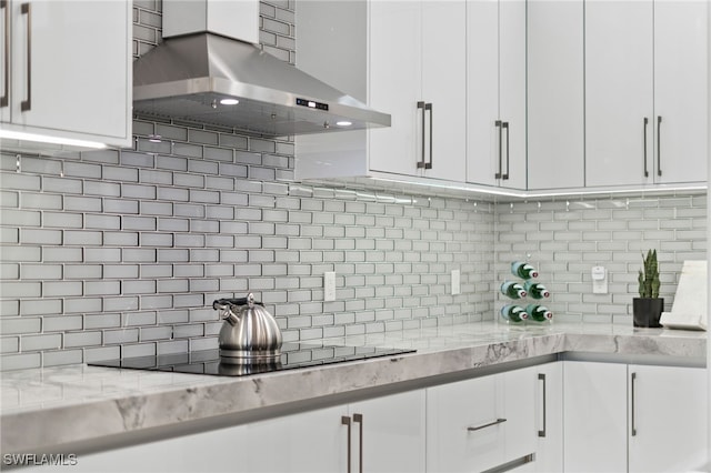 kitchen featuring tasteful backsplash, white cabinets, and wall chimney exhaust hood