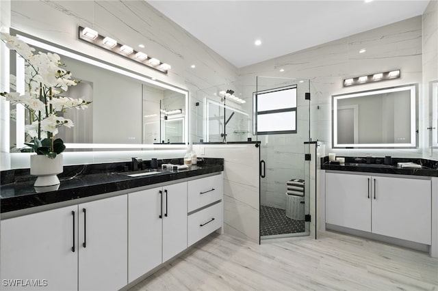 bathroom featuring vanity, wood-type flooring, a shower with door, and vaulted ceiling