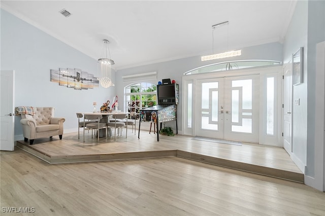 foyer entrance featuring a chandelier, light hardwood / wood-style floors, and crown molding