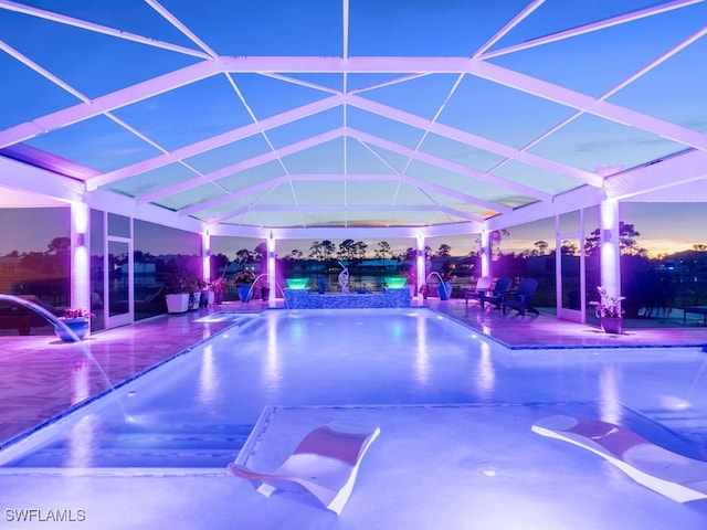 view of pool with pool water feature, glass enclosure, and a patio area