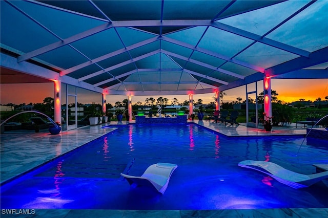 pool at dusk with a lanai, a patio, and a hot tub