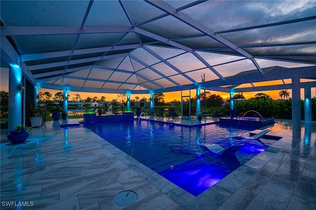 pool at dusk with pool water feature, glass enclosure, a patio, and a hot tub