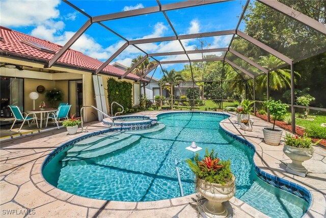 view of swimming pool featuring glass enclosure, an in ground hot tub, and a patio area