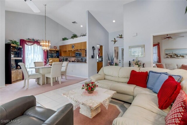 living room with ceiling fan with notable chandelier, high vaulted ceiling, and light tile patterned floors