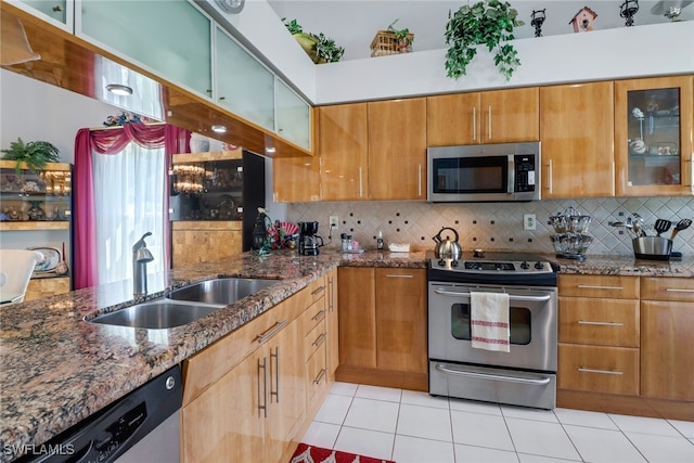 kitchen featuring light tile patterned floors, stainless steel appliances, decorative backsplash, and stone countertops