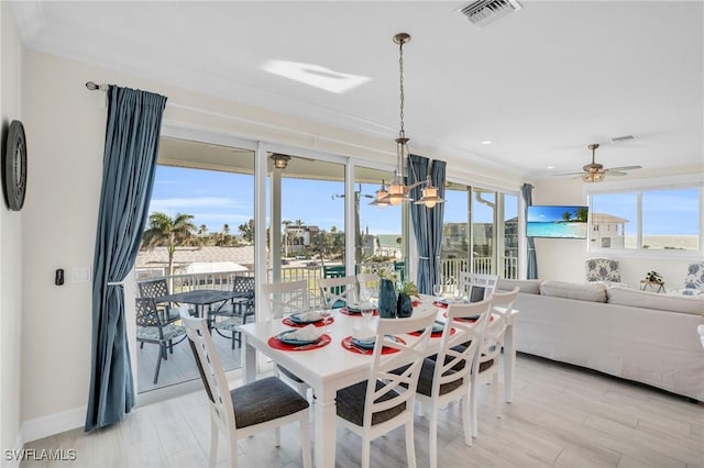 dining area with light wood-type flooring, visible vents, baseboards, and ceiling fan with notable chandelier