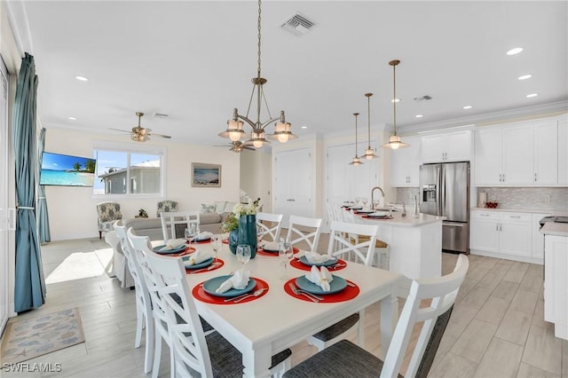 dining space with crown molding, recessed lighting, visible vents, light wood-style flooring, and ceiling fan with notable chandelier