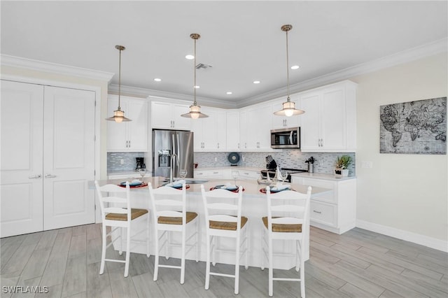 kitchen with light countertops, appliances with stainless steel finishes, a kitchen island with sink, white cabinets, and a sink