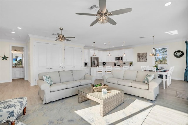 living room featuring recessed lighting, visible vents, baseboards, ornamental molding, and light wood finished floors