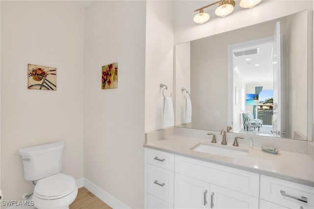 bathroom with baseboards, vanity, toilet, and wood finished floors