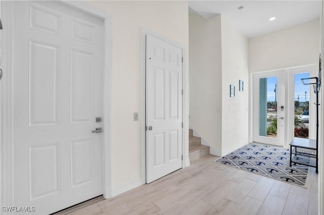 foyer featuring stairway, light wood-style flooring, and baseboards