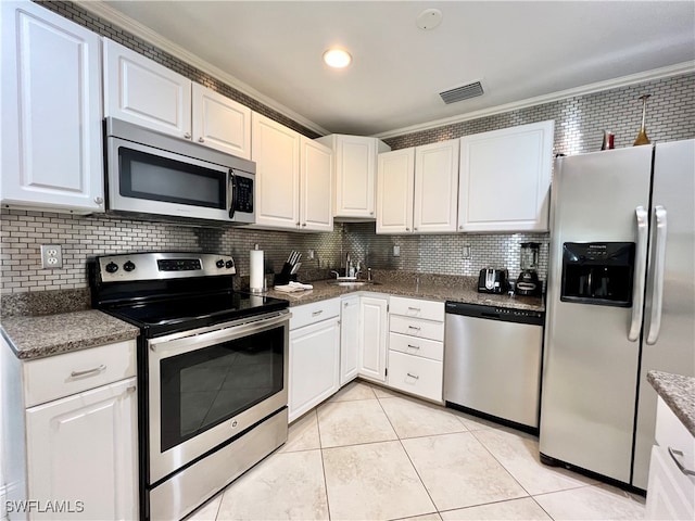 kitchen with stainless steel appliances, decorative backsplash, and white cabinetry