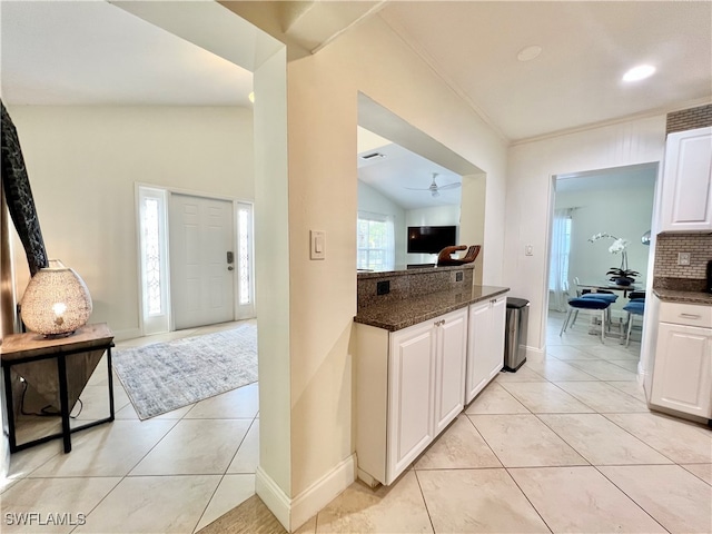 kitchen featuring light tile patterned floors, backsplash, lofted ceiling, ceiling fan, and white cabinets