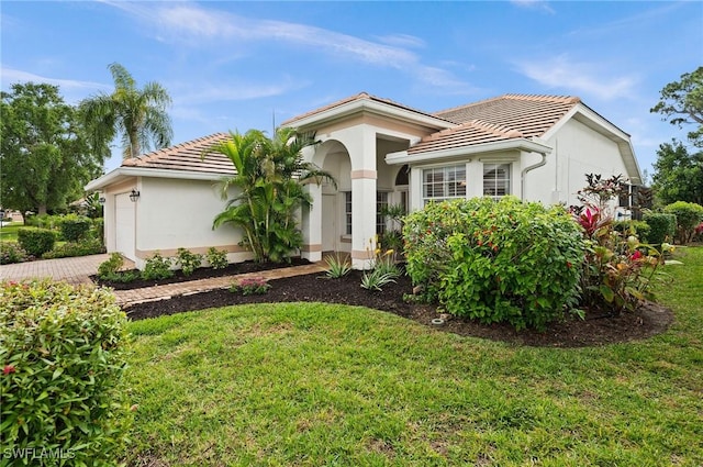 mediterranean / spanish house with a garage, driveway, a tile roof, and stucco siding