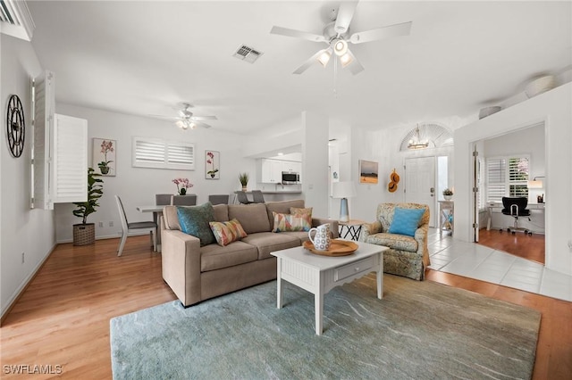 living area with baseboards, ceiling fan, visible vents, and wood finished floors