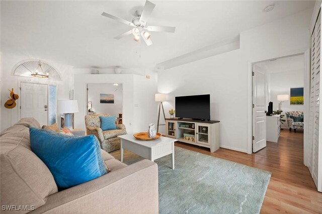 living room with wood-type flooring and ceiling fan with notable chandelier