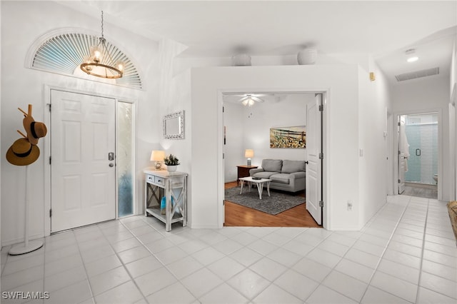 foyer with a chandelier, light tile patterned floors, vaulted ceiling, and a healthy amount of sunlight