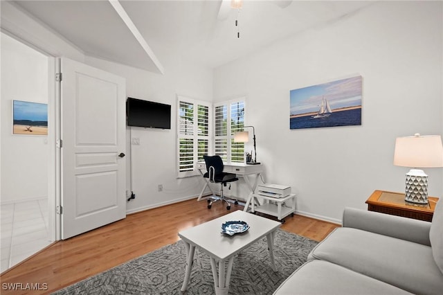 living area with a ceiling fan, baseboards, and wood finished floors