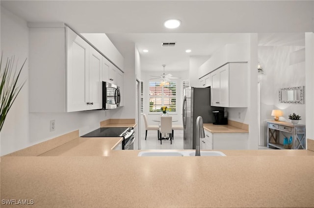 kitchen featuring stainless steel appliances, light countertops, visible vents, white cabinets, and a sink