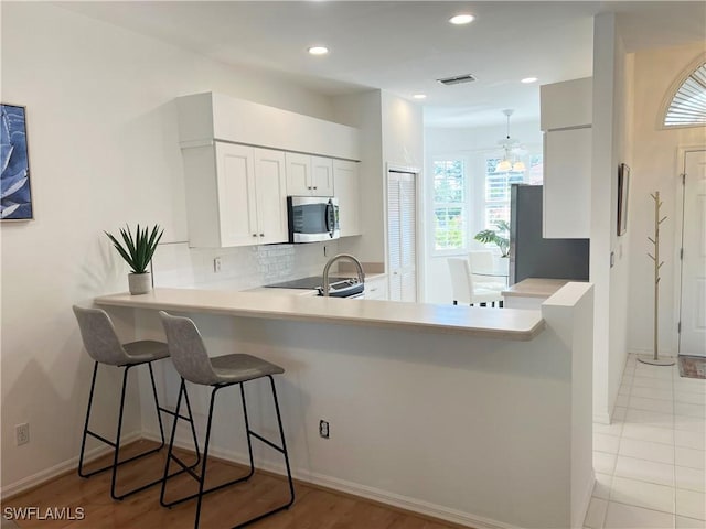 25040 Bay Cedar Dr, Bonita Springs, FL 34134 - kitchen featuring visible vents, light countertops, stainless steel appliances, decorative backsplash, and a breakfast bar area