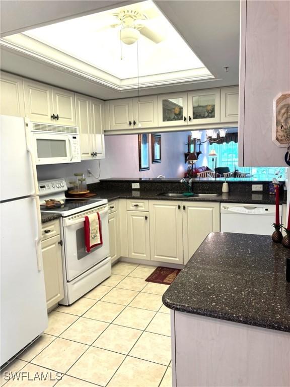 kitchen with sink, light tile patterned floors, white appliances, and a tray ceiling