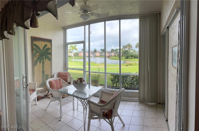 sunroom featuring a water view and ceiling fan