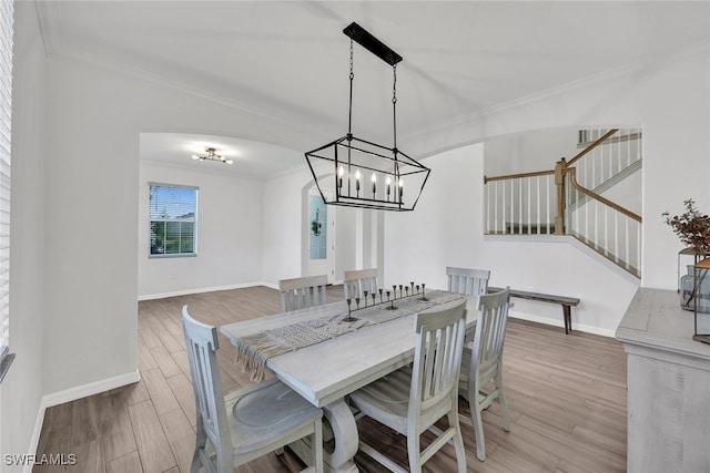 dining space with crown molding, an inviting chandelier, and light hardwood / wood-style floors