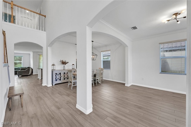 interior space featuring crown molding, a chandelier, and light hardwood / wood-style floors