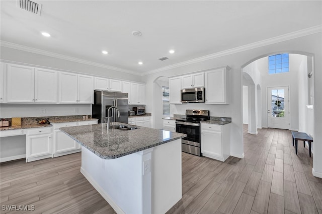 kitchen featuring a center island with sink, appliances with stainless steel finishes, light hardwood / wood-style floors, sink, and white cabinets