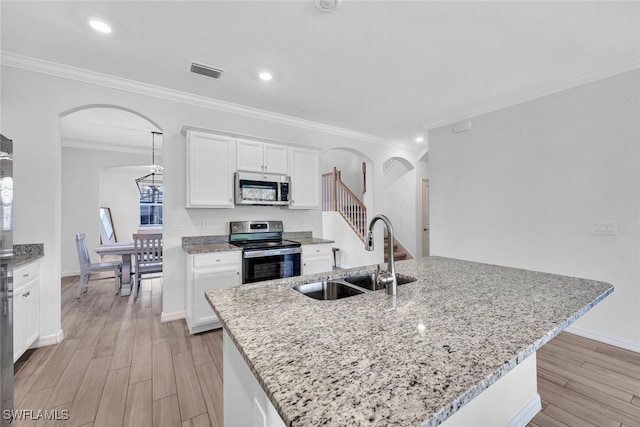 kitchen with a kitchen island with sink, light hardwood / wood-style flooring, sink, appliances with stainless steel finishes, and white cabinets