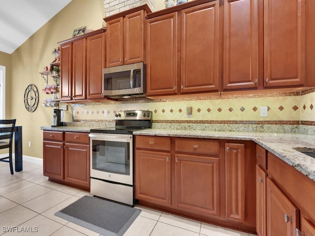 kitchen featuring light tile patterned flooring, stainless steel appliances, backsplash, light stone countertops, and lofted ceiling