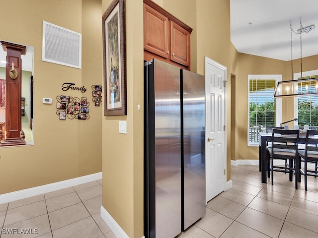 kitchen with hanging light fixtures, light tile patterned floors, lofted ceiling, and stainless steel fridge