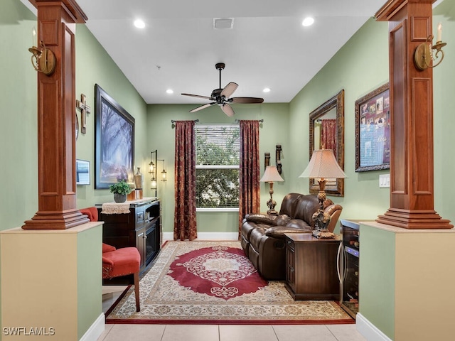 living room featuring light tile patterned floors, ceiling fan, and ornate columns