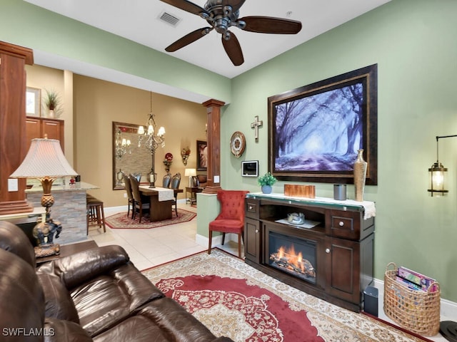 tiled living room with ornate columns and ceiling fan with notable chandelier