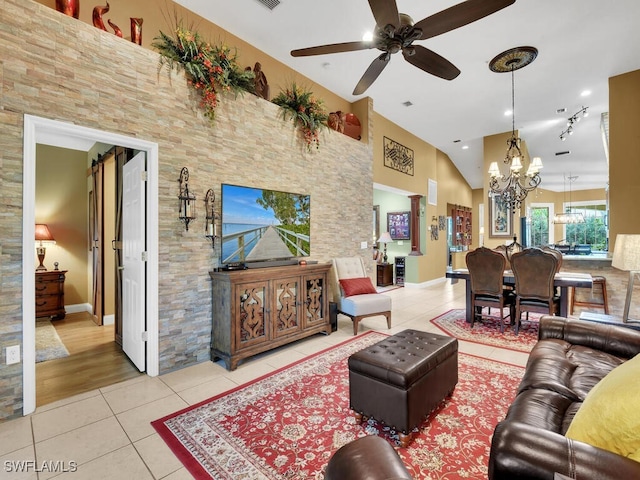 tiled living area featuring baseboards, high vaulted ceiling, and ceiling fan with notable chandelier