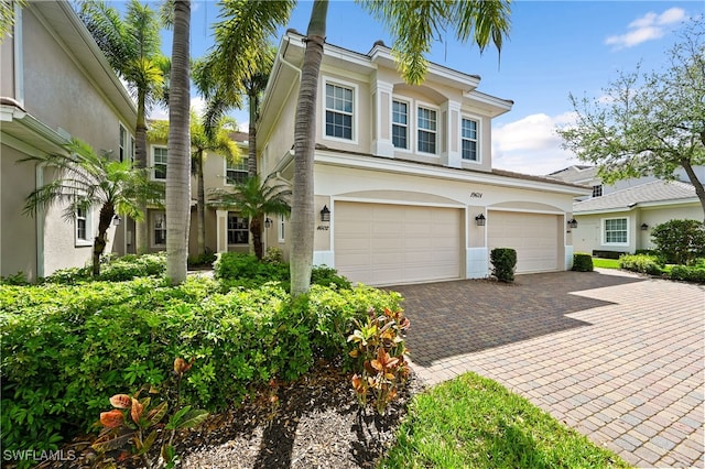 view of front facade with an attached garage, decorative driveway, and stucco siding