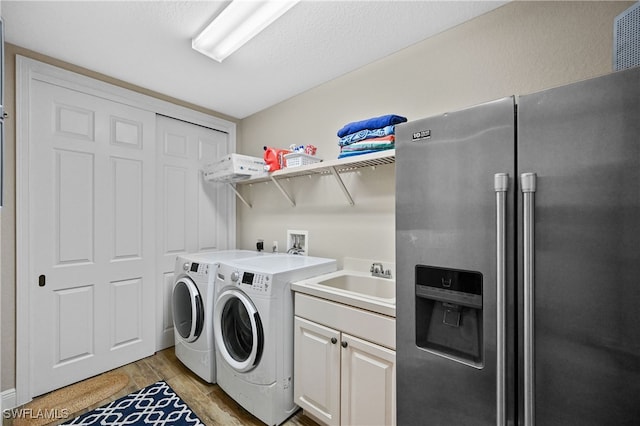 laundry room featuring washer and dryer, light hardwood / wood-style flooring, cabinets, and sink