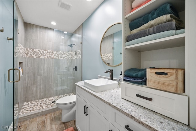 full bath featuring vanity, wood finished floors, a shower stall, and toilet