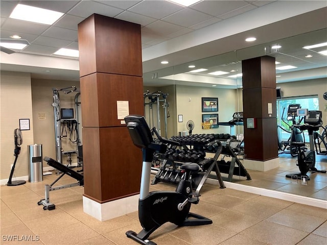 exercise room with a paneled ceiling and baseboards