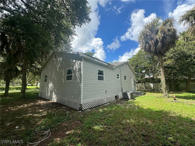 view of side of property with central AC and a yard