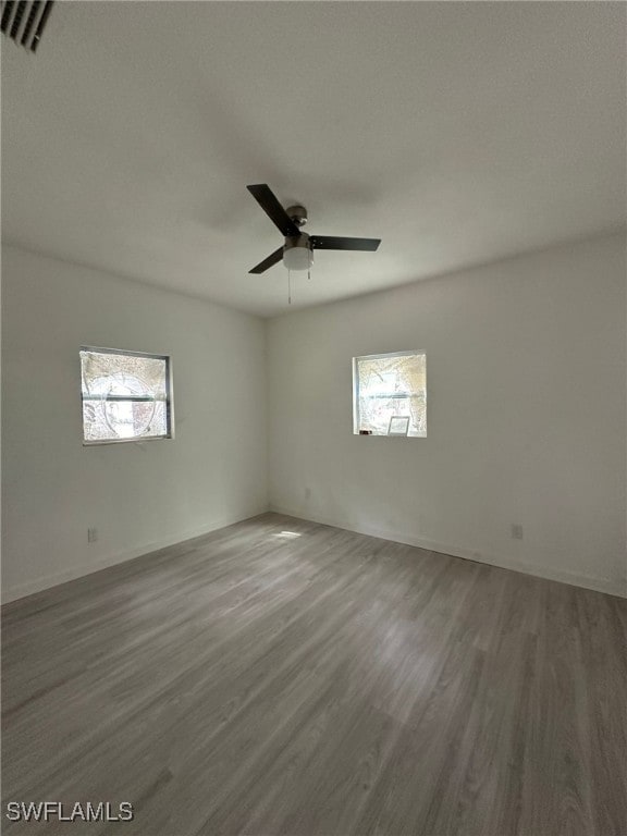 empty room with hardwood / wood-style floors, ceiling fan, and plenty of natural light