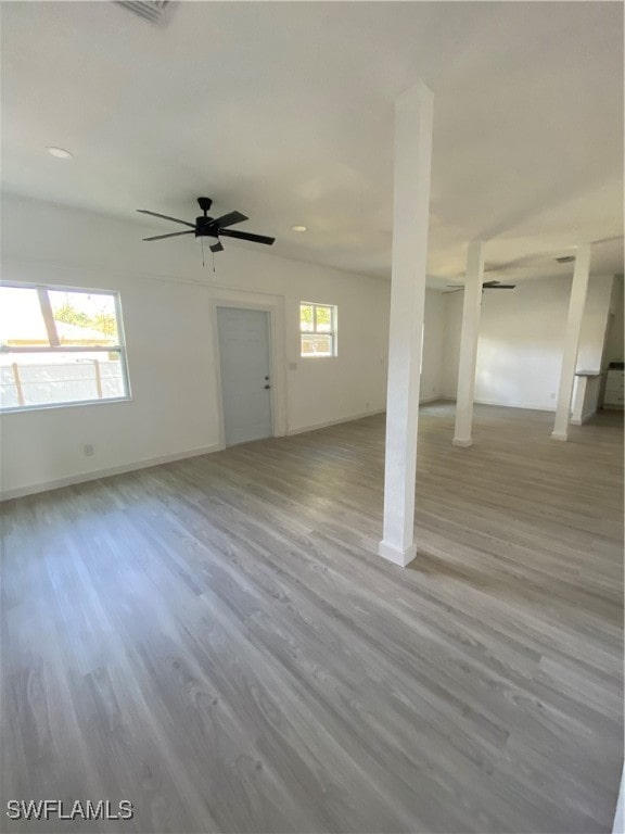 unfurnished living room with light wood-type flooring, a wealth of natural light, and ceiling fan