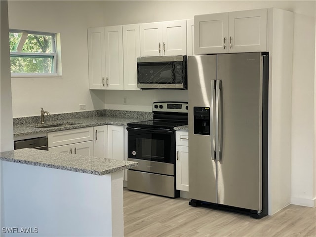 kitchen with light wood-type flooring, appliances with stainless steel finishes, sink, and white cabinets