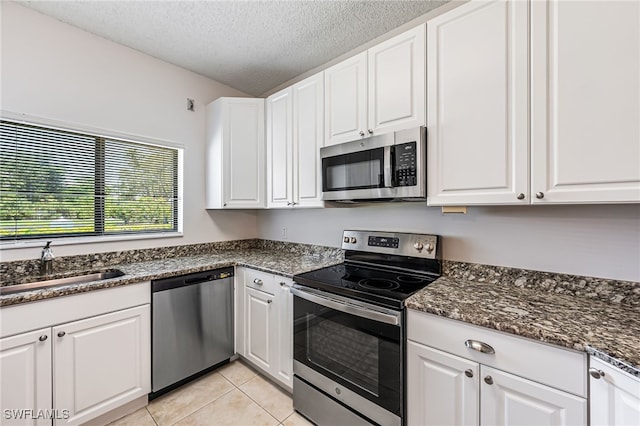 kitchen featuring white cabinets, light tile patterned floors, a textured ceiling, and stainless steel appliances