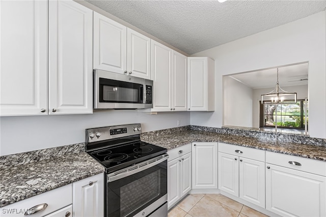 kitchen with stainless steel appliances, dark stone counters, a chandelier, a textured ceiling, and white cabinets