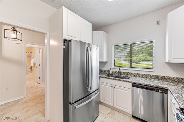 kitchen with stone counters, stainless steel appliances, white cabinetry, and sink