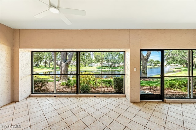 unfurnished sunroom featuring ceiling fan and a water view