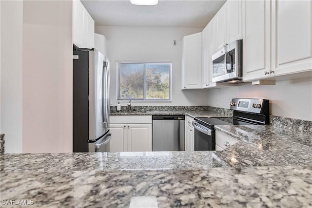 kitchen featuring white cabinets, light stone counters, and appliances with stainless steel finishes