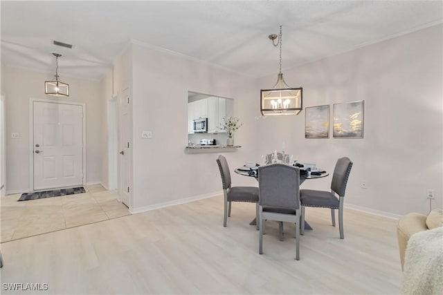 dining space featuring a chandelier, light wood-type flooring, baseboards, and ornamental molding